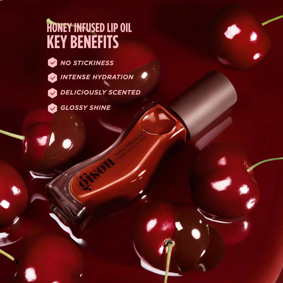 Rust-red lip oil bottle lying among glossy cherries in red liquid, with key benefits like no stickiness listed