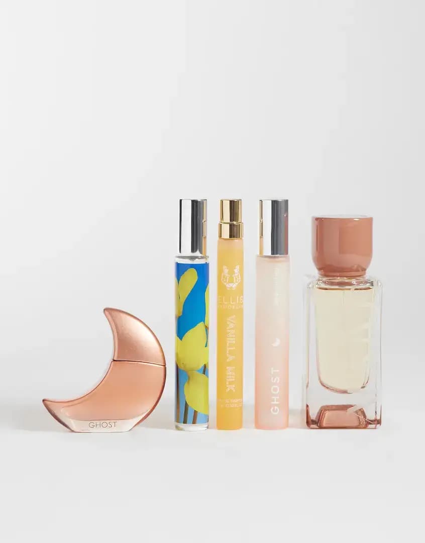 Ghost moon bottle, three slim travel sprays and a square ARKIVE bottle with peach cap lined up on white