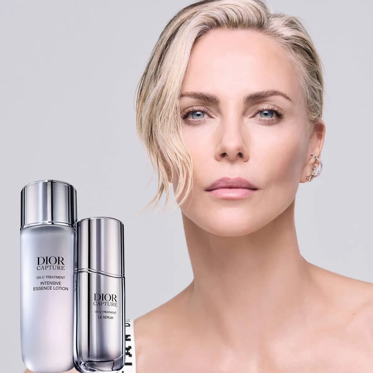 Charlize Theron with wavy blonde hair beside the Intensive Essence Lotion and Le Sérum bottles on a grey background.