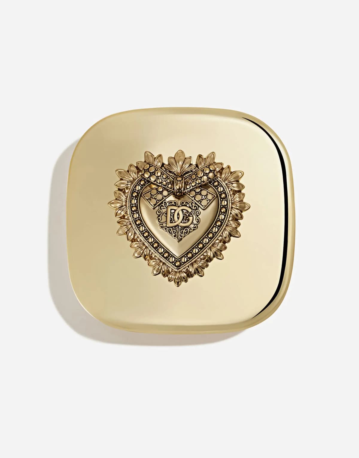 Top view of the closed gold compact lid with an ornate raised heart emblem and DG logo