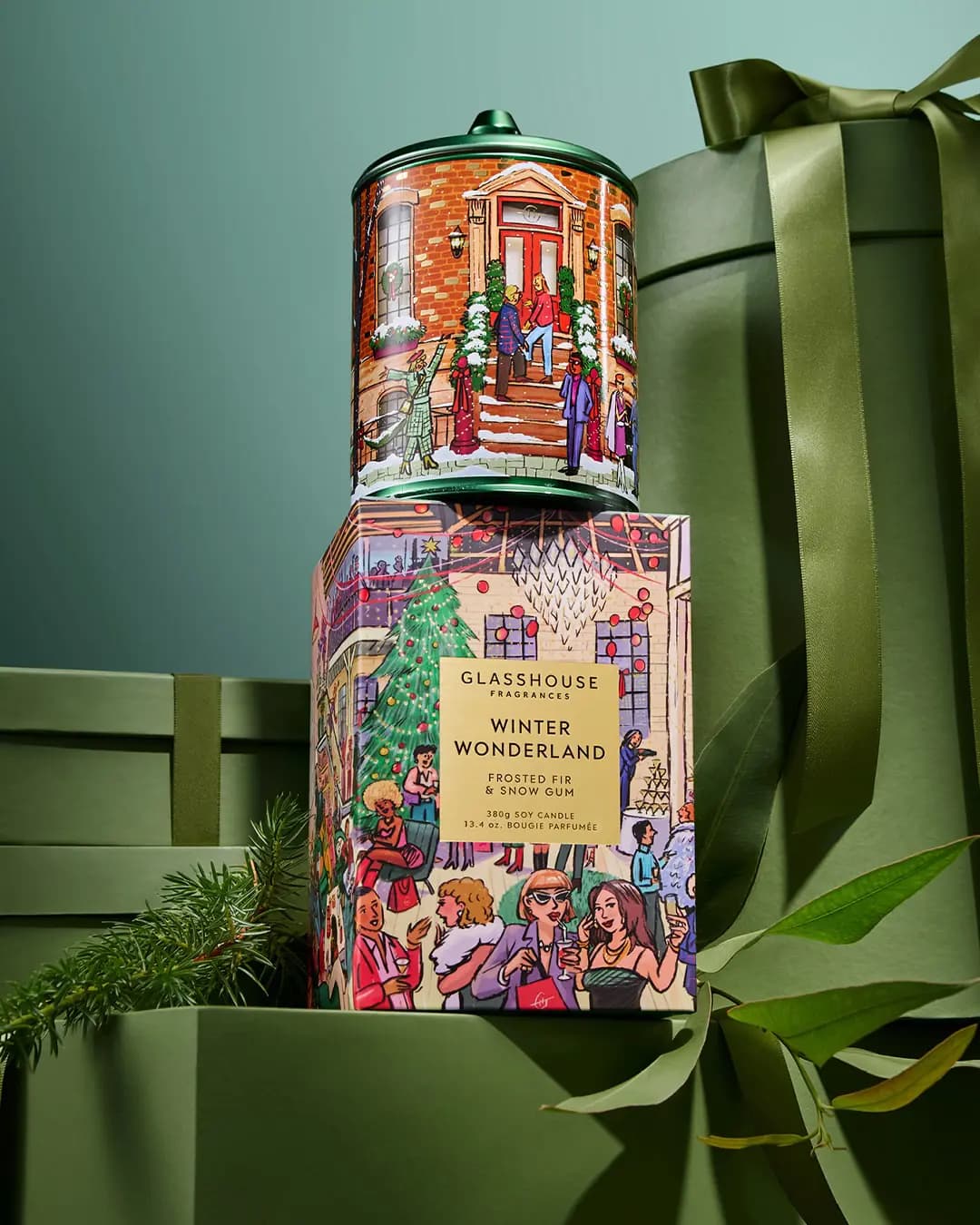 Glasshouse Winter Wonderland green-lidded brownstone tin stacked on its party-scene box against green gift boxes