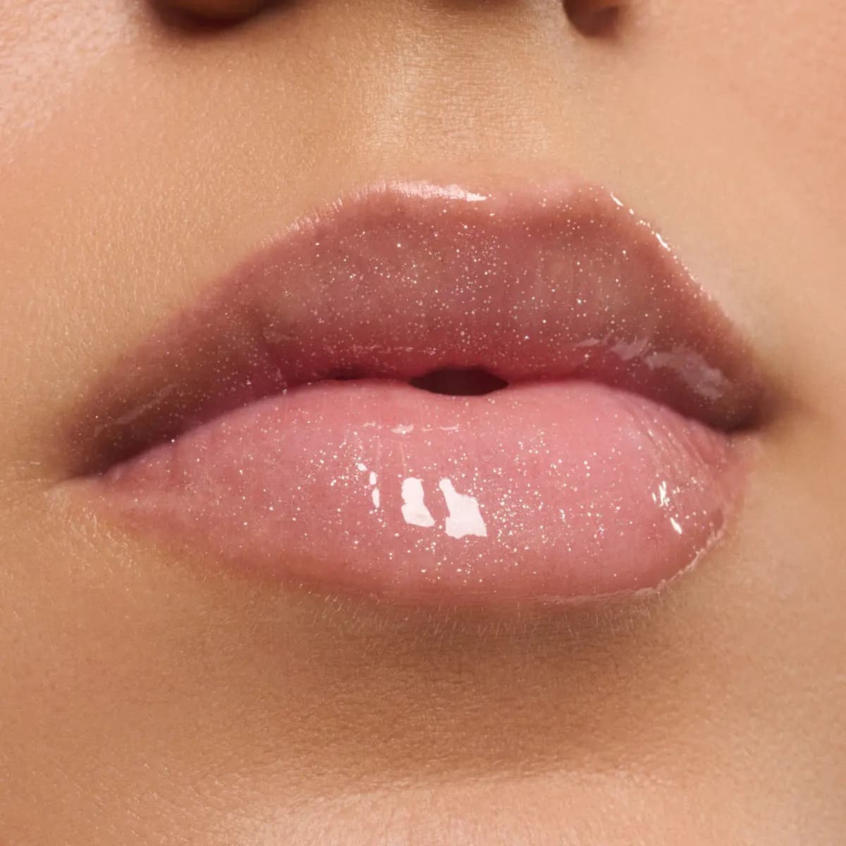 Close-up of plump lips wearing a sheer silver-pink sparkly gloss
