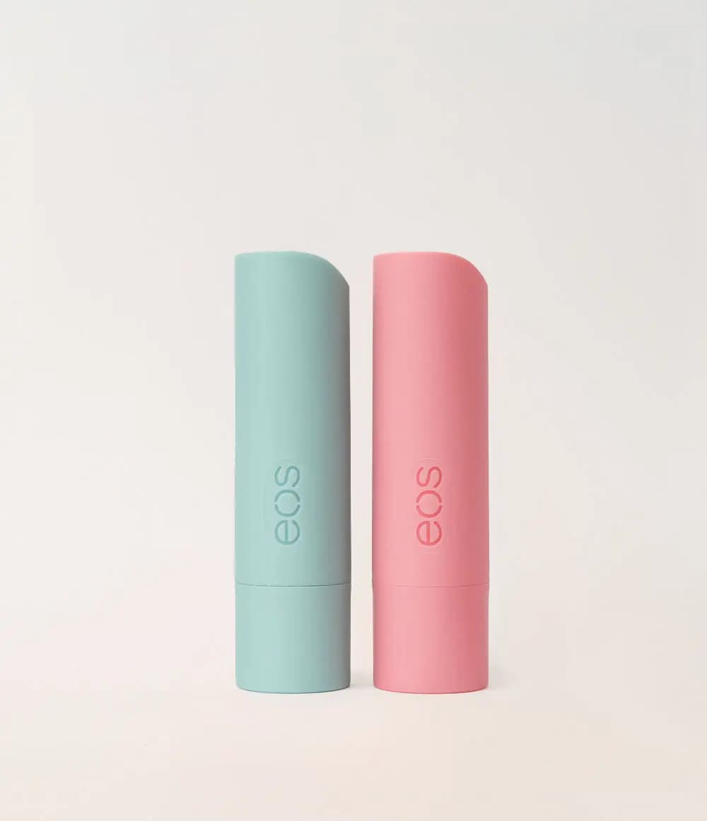 Mint green and pink eos lip balm sticks standing side by side on a plain cream background