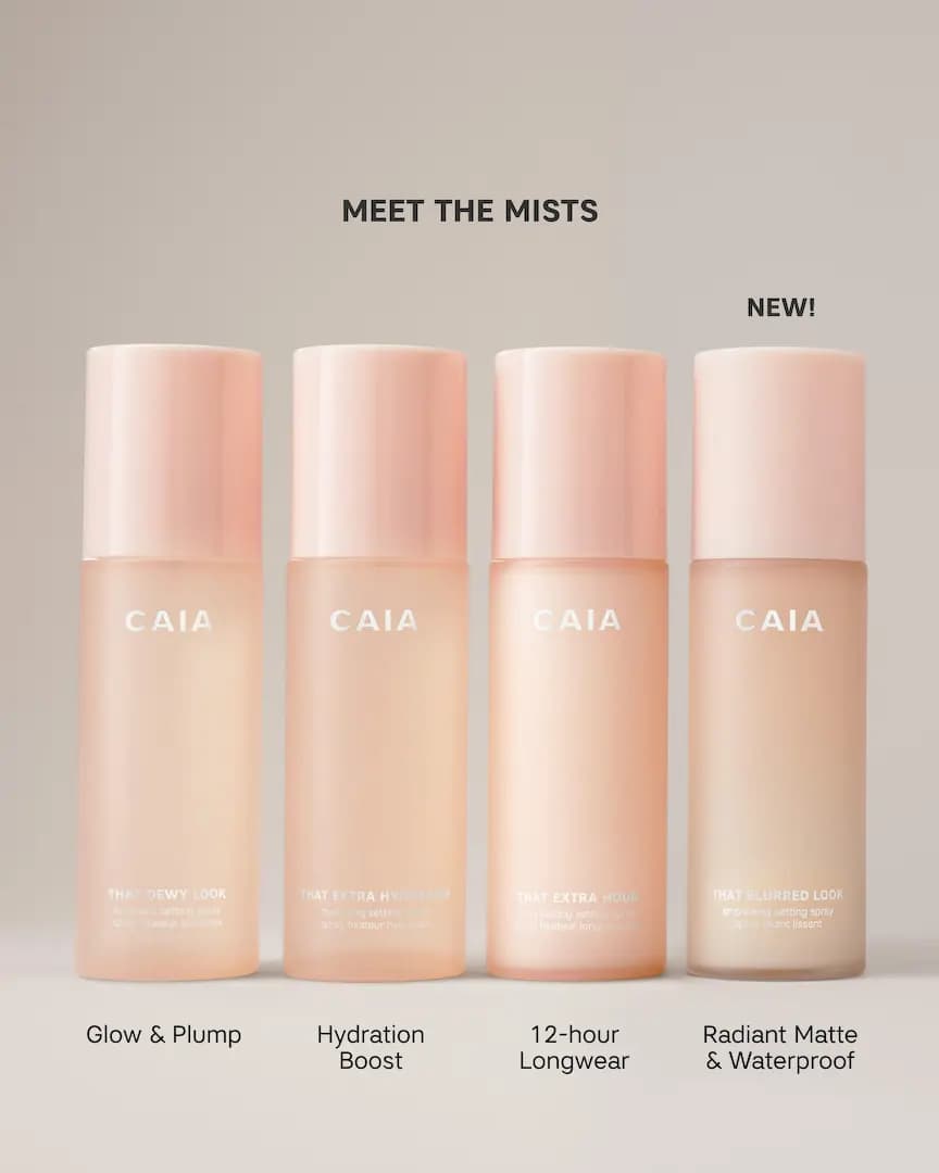 Four peach CAIA setting spray bottles in a row, with That Blurred Look marked NEW for radiant matte and waterproof wear
