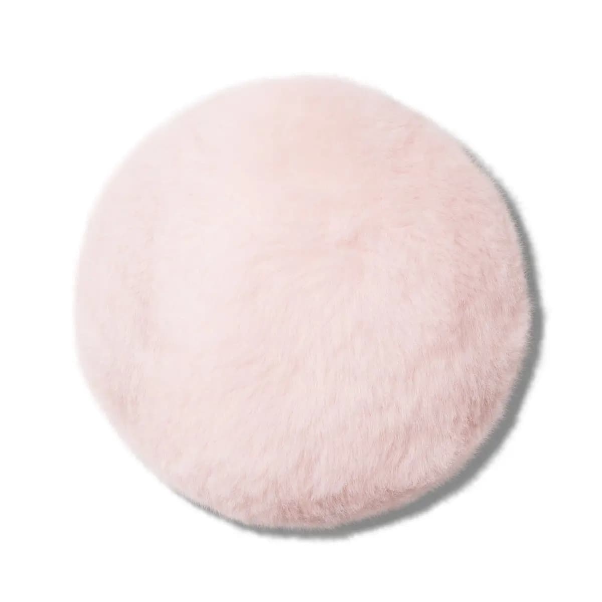 Underside of the round, ultra-fluffy pale pink puff without its strap, on a white background