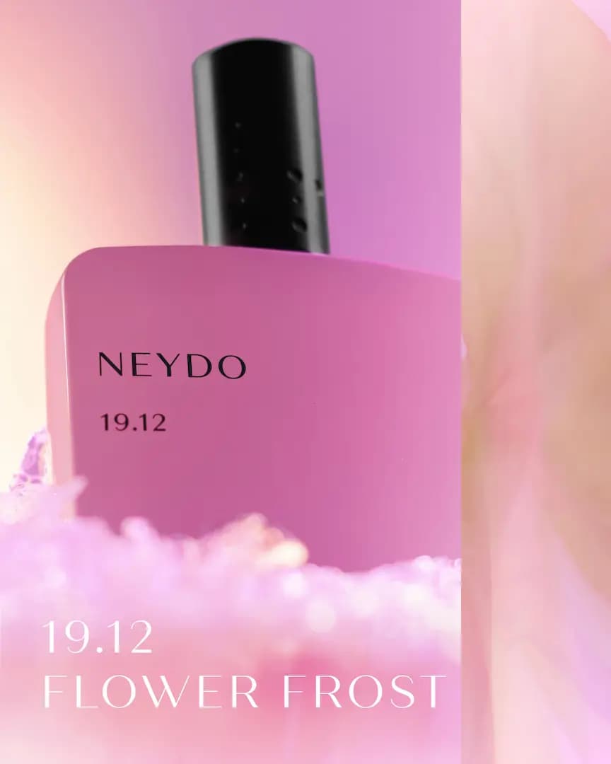 Close-up of lilac NEYDO 19.12 Flower Frost bottle rising from pink frosty crystals with title text overlay