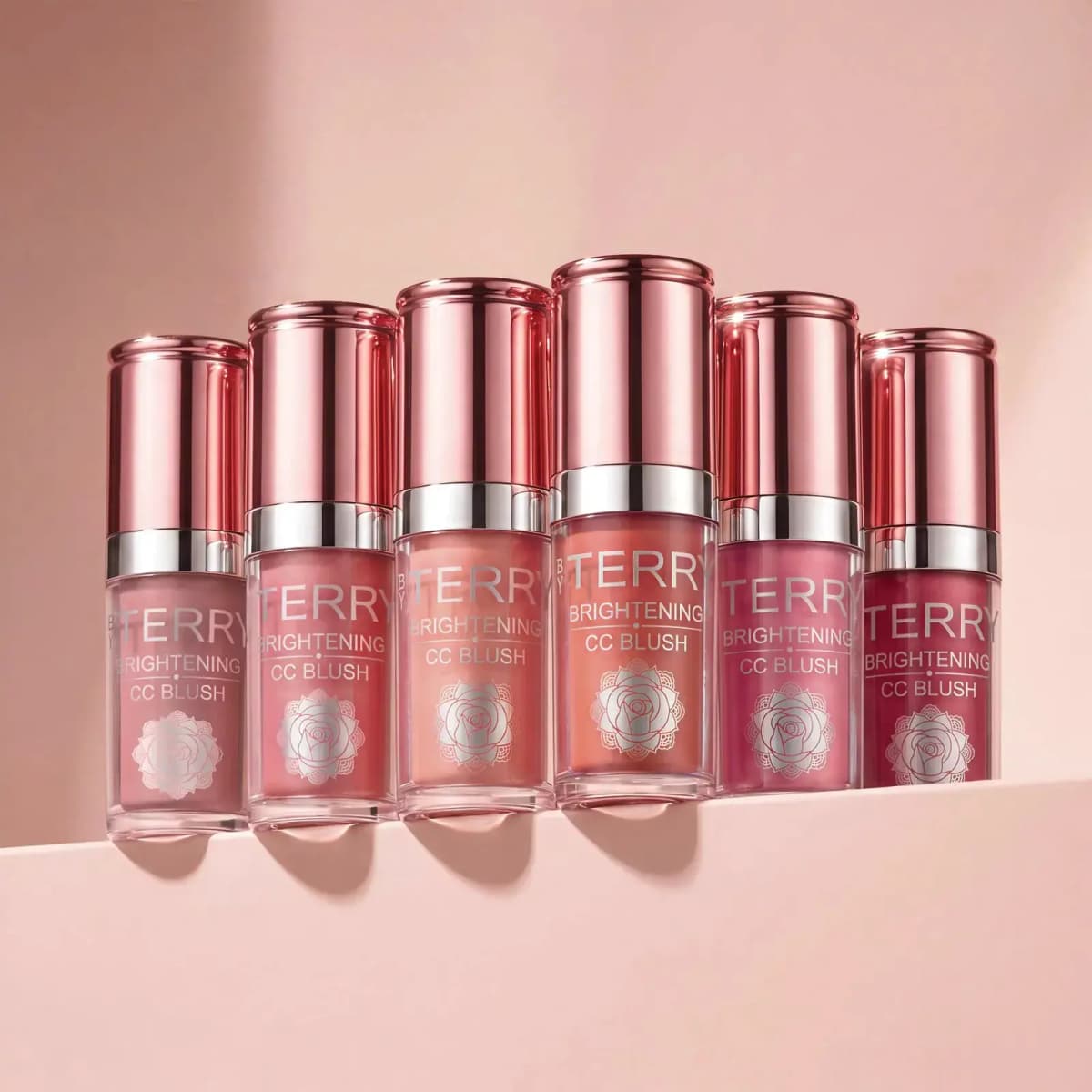By Terry Brightening CC Blush liquid blush bottles in six shades with rose-gold caps lined up on a pink ledge
