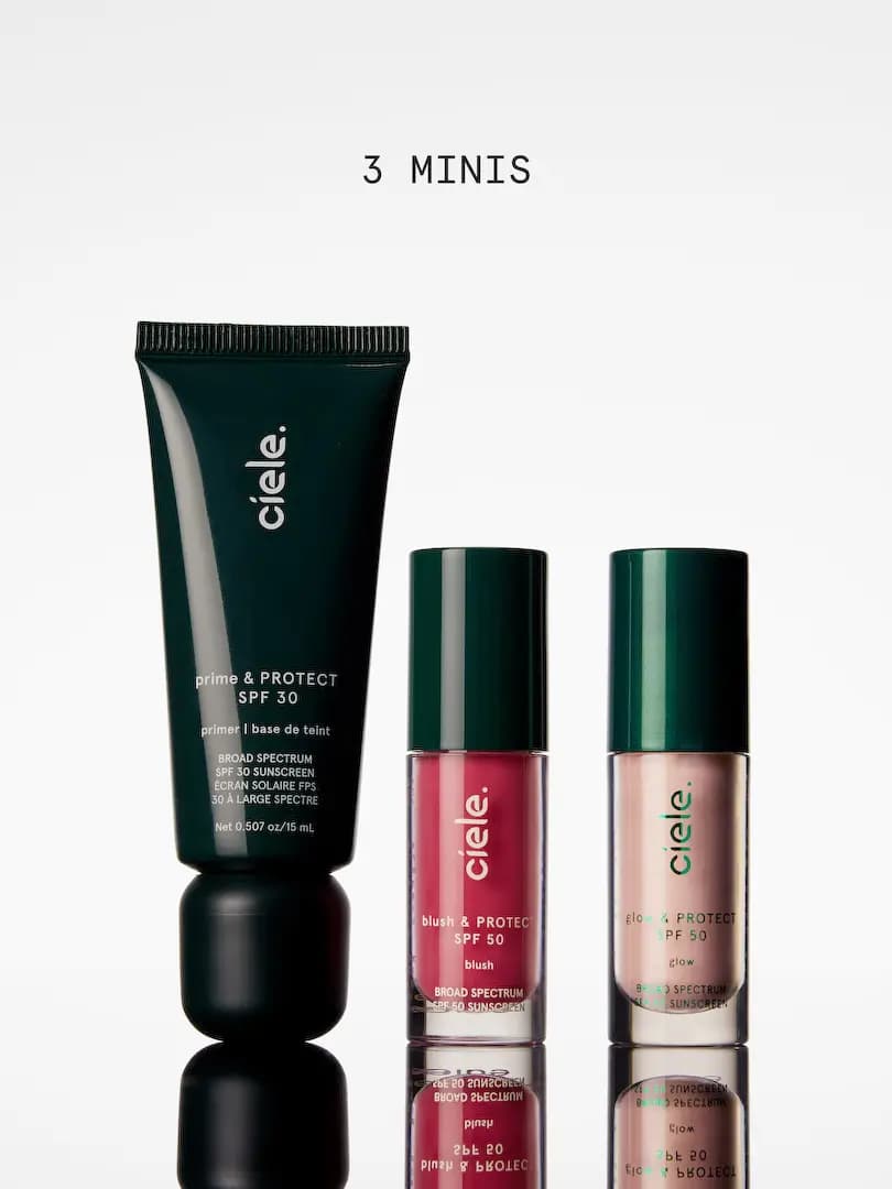 Three minis on a reflective surface: dark green prime & PROTECT SPF 30 tube, berry blush and pink glow bottles