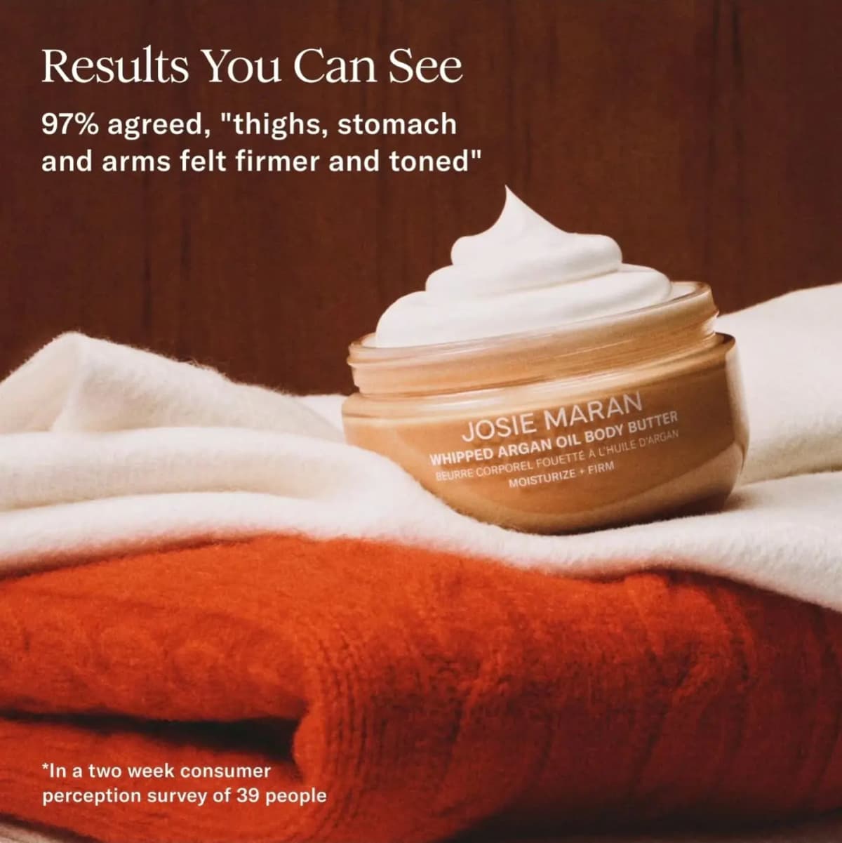 Jar of Whipped Argan Oil Body Butter topped with a swirl of cream on white and orange knits, with a 97% firmness claim