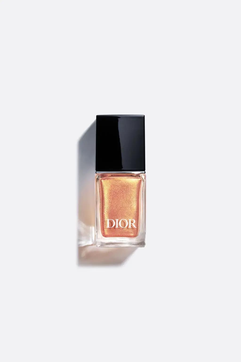 Dior nail lacquer bottle with a black cap and shimmering peach-gold polish