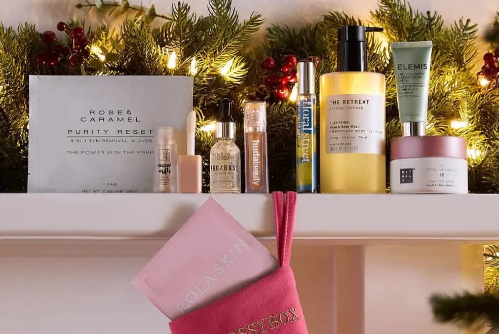 Stocking products incl. Elemis, The Retreat and Rituals on a garlanded mantel, Rolaskin mask in a pink GLOSSYBOX stocking