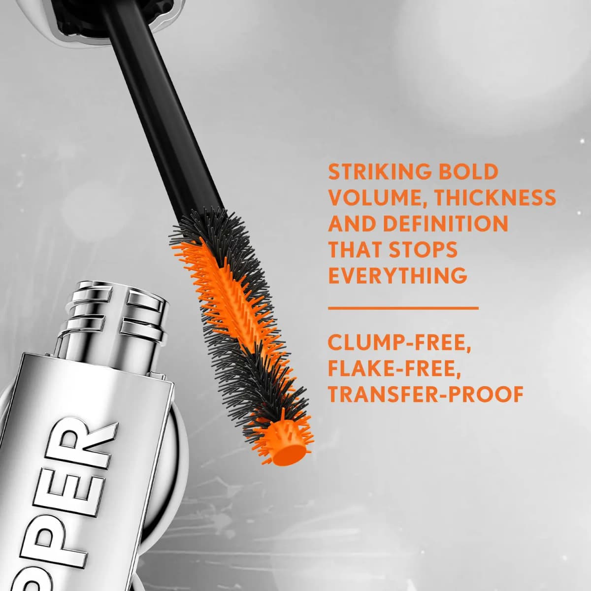 Mascara wand rising from an open chrome tube beside claims of bold volume and clump-free, flake-free, transfer-proof wear