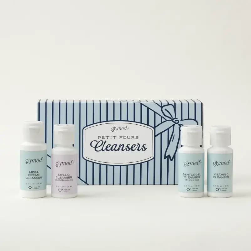 GlyMed+ Petit Fours Cleansers set: four mini cleanser bottles before a pale blue and navy striped box with a bow