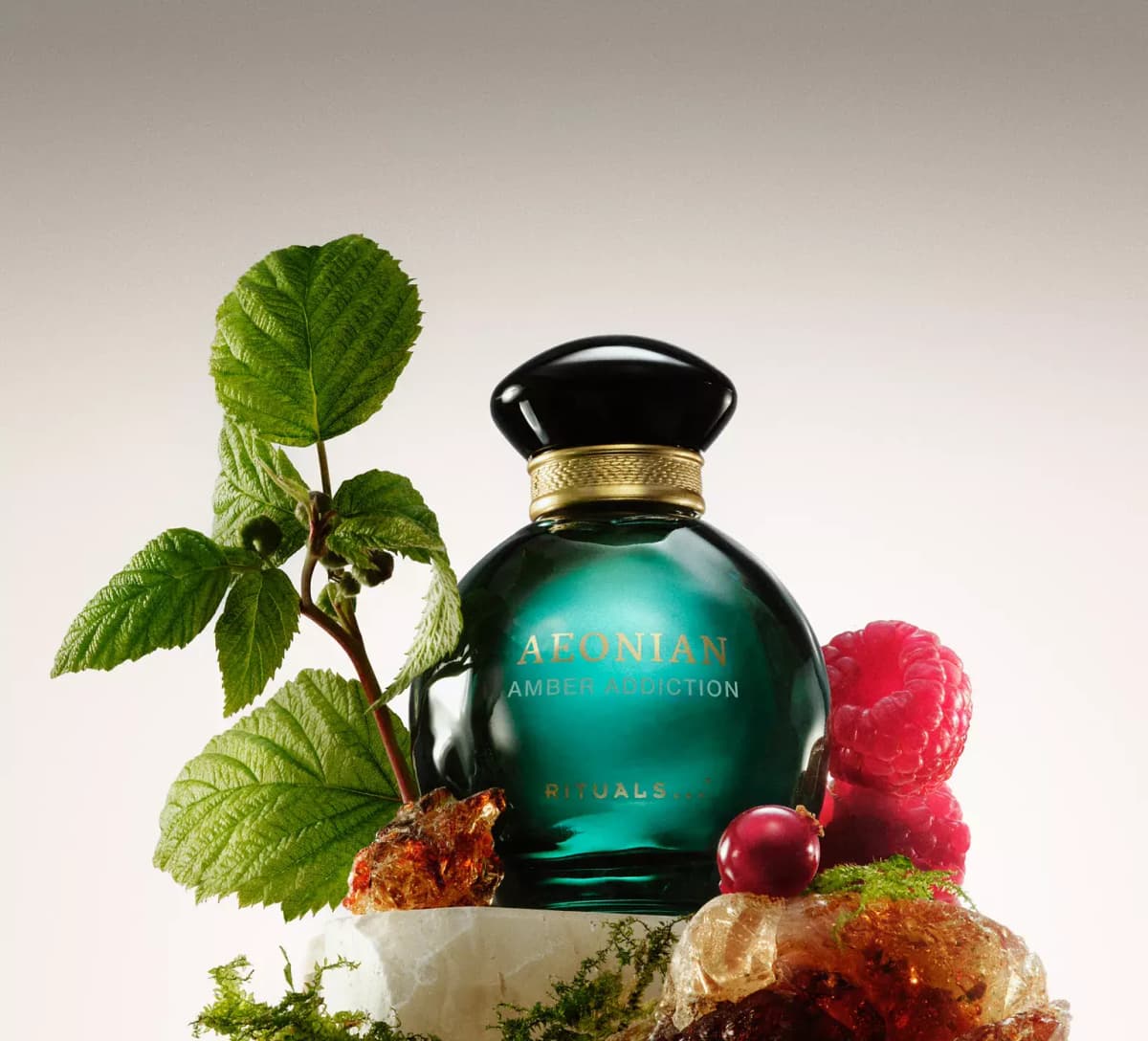 Rituals Aeonian Amber Addiction teal bottle with raspberry leaves, raspberries, a red berry, amber resin chunks and moss