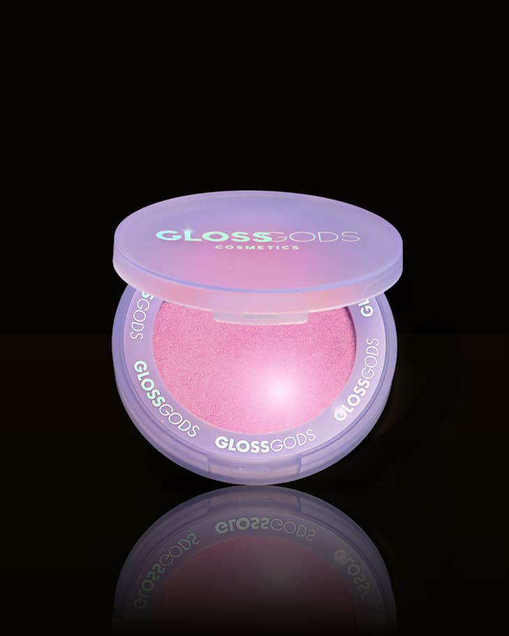 Lilac compact with iridescent lid open to reveal a shimmering pink pressed powder