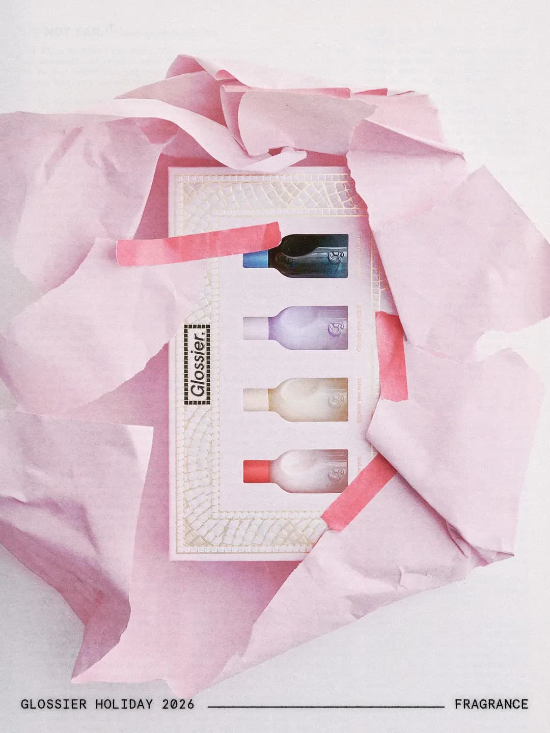 Mini Glossier You kit with four bottles, from red to navy caps, nestled in torn pink wrapping paper