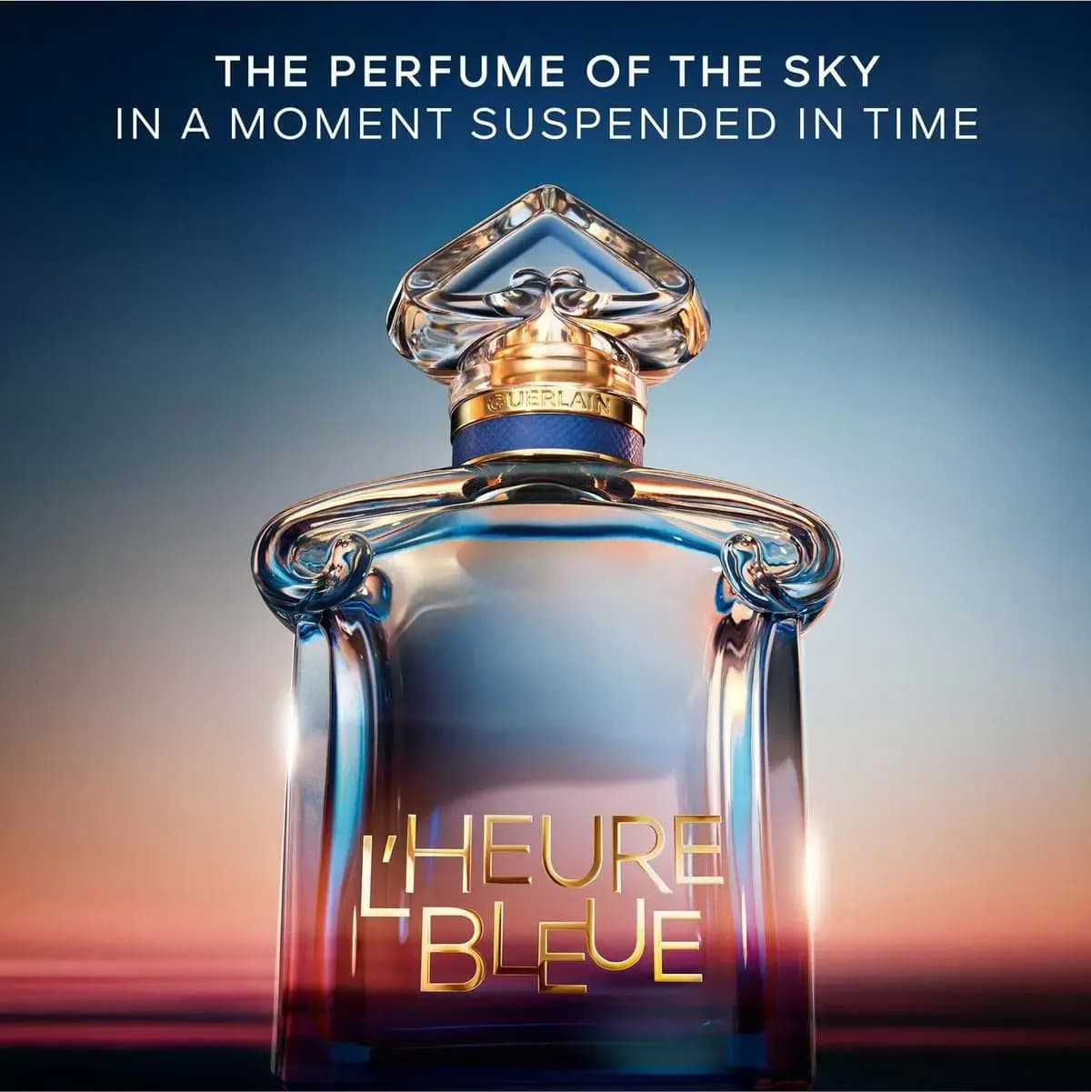 L'Heure Bleue bottle glowing against a blue-to-peach sunset with text: the perfume of the sky in a moment suspended in time.