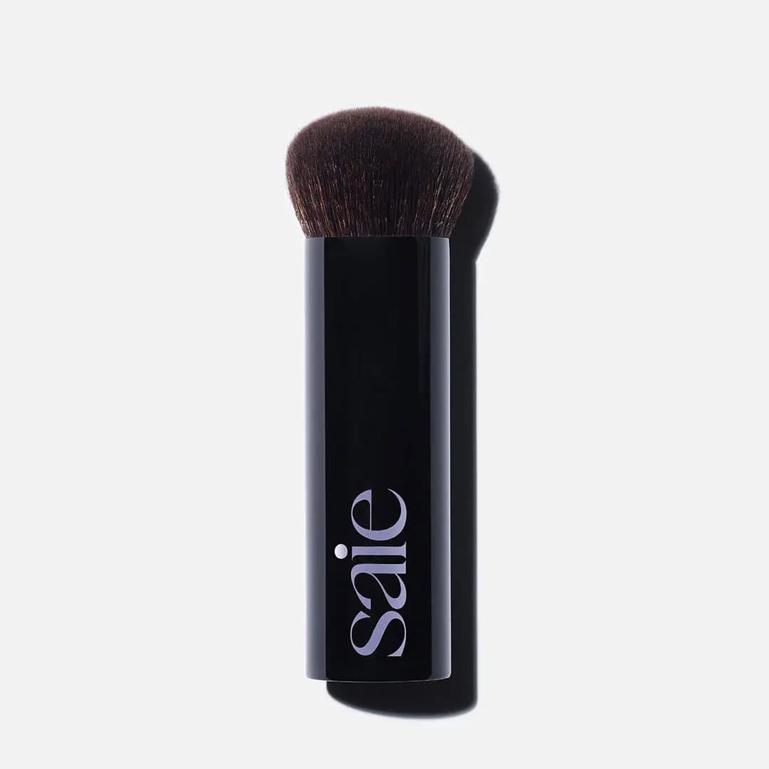 Short dense domed buffing brush with wide glossy black Saie handle casting a shadow