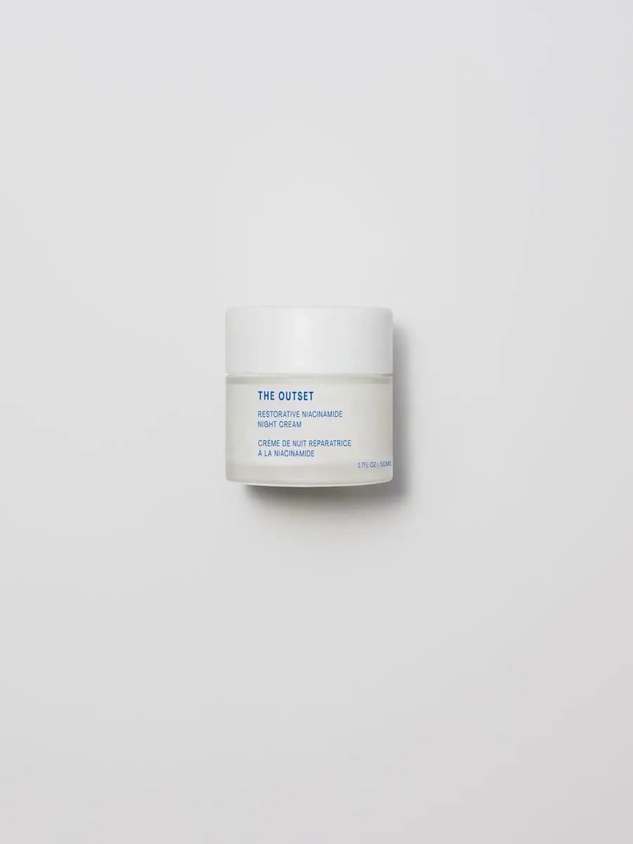 The Outset Restorative Niacinamide Night Cream in a frosted 50ml jar with a white lid on a grey backdrop