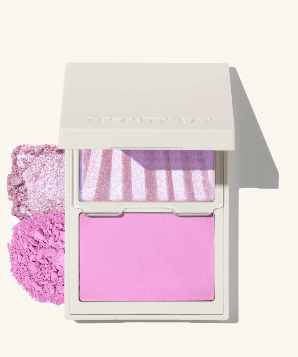 White compact with lilac striped colour-shifting highlighter over matte pink powder, with crushed swatches