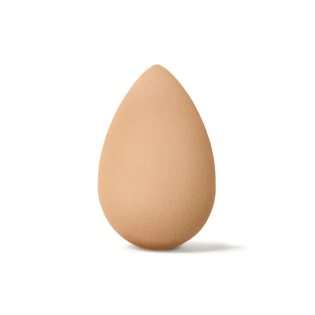 Single nude teardrop-shaped makeup sponge standing upright on a plain white background