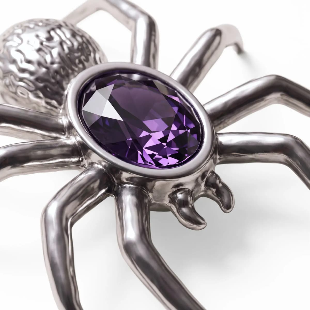 Close-up of silver spider pin with faceted oval purple stone and textured abdomen