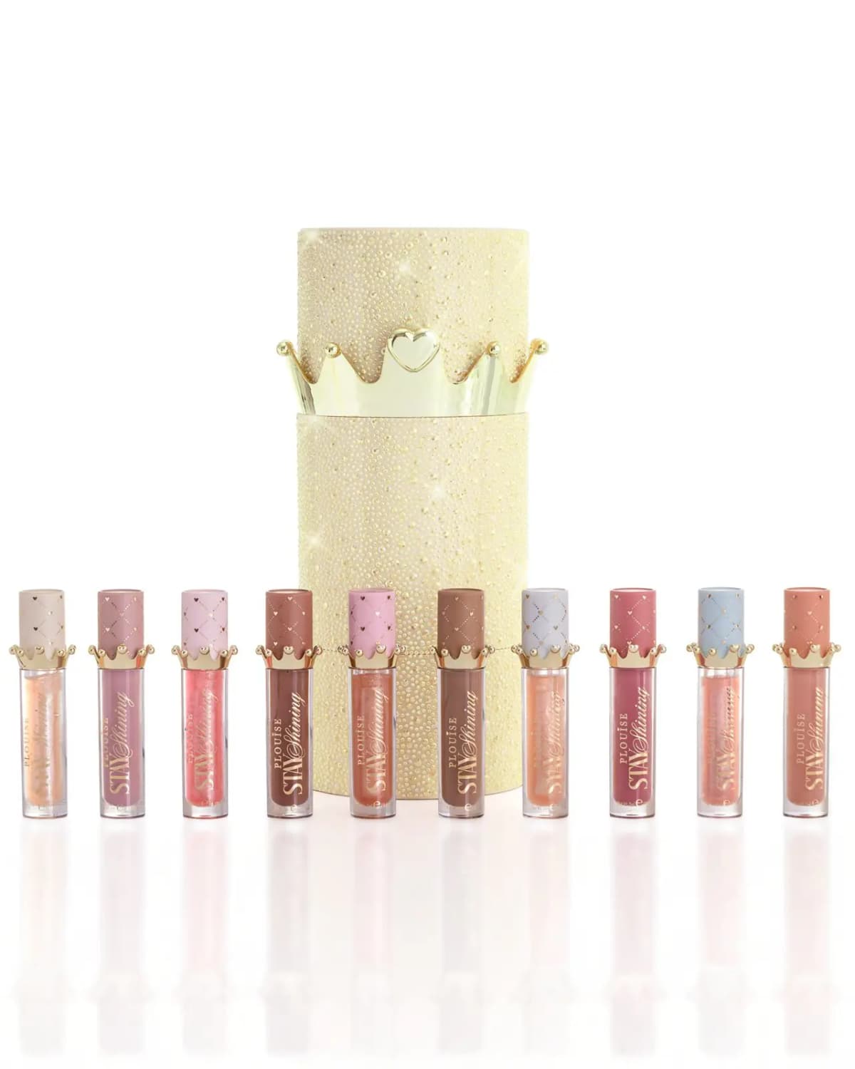Ten Stay Shining glosses in nude, pink and berry shades lined up before a gold crystal-studded crown tube