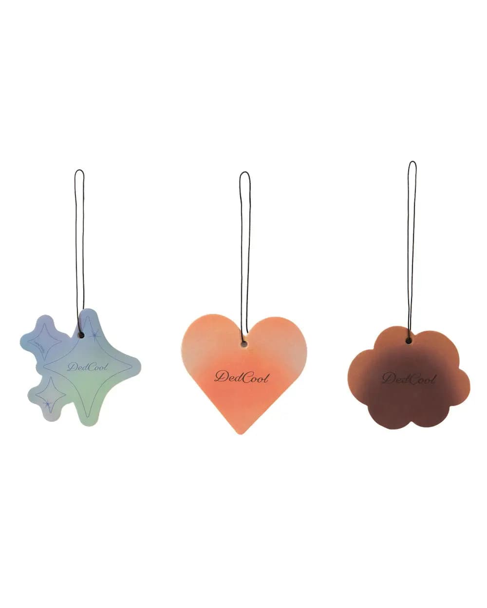 Three hanging air fresheners shaped as an iridescent star, orange heart and brown cloud