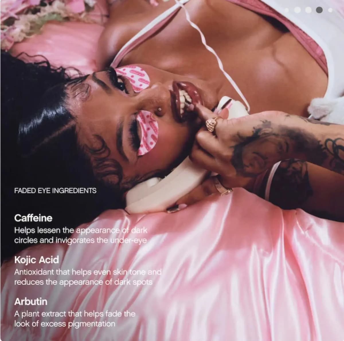 Model lies on pink satin wearing pink Faded eye masks beside text on caffeine, kojic acid and arbutin