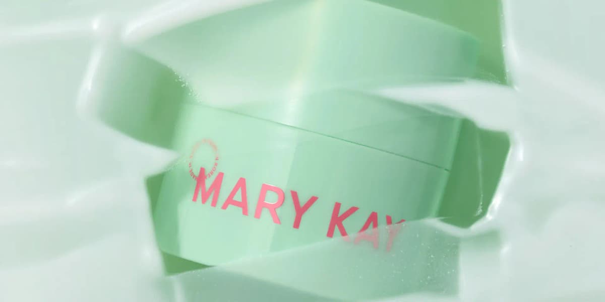 Mint green Mary Kay cleansing balm jar partly submerged in swirling milky white liquid