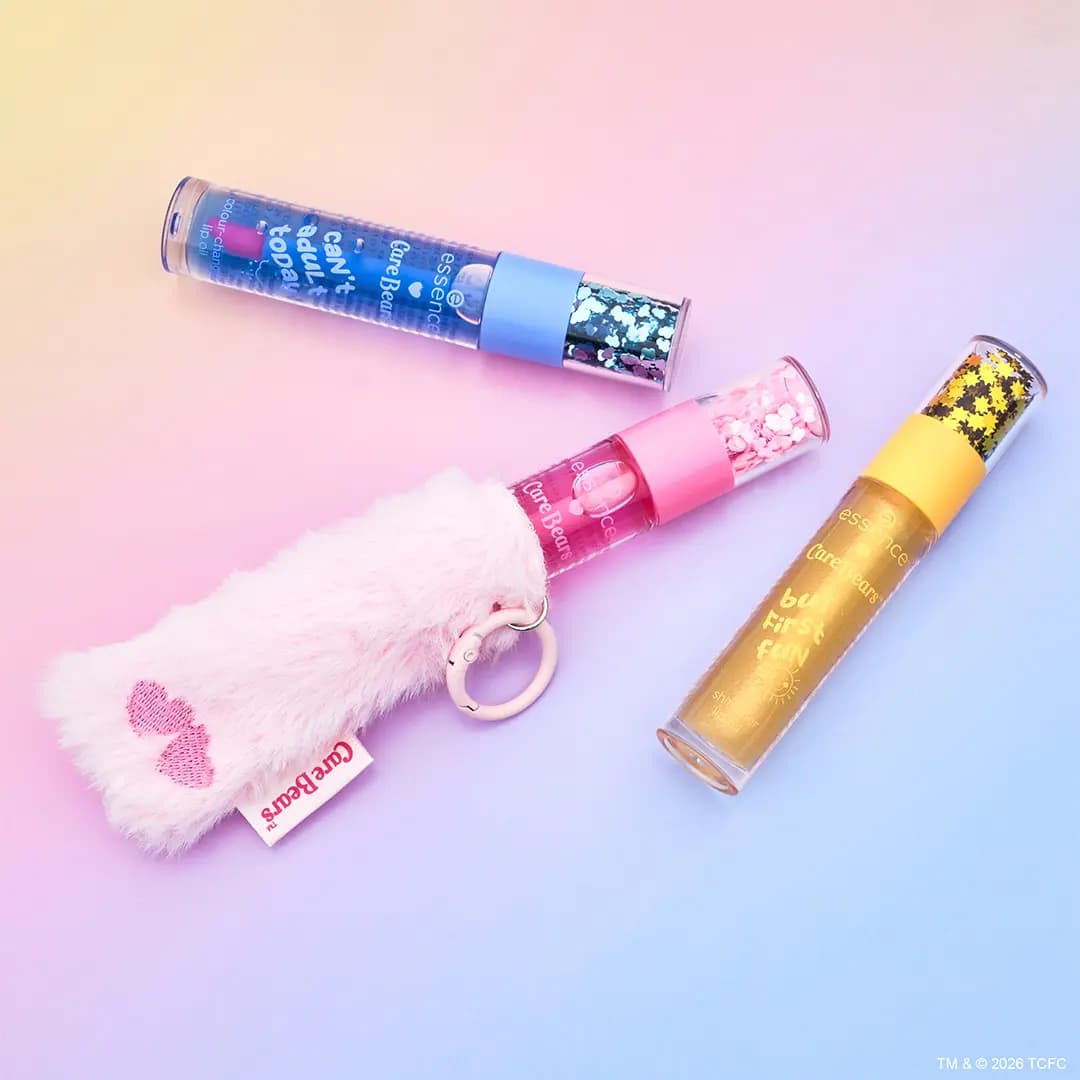 Three lip oils in blue, pink and yellow tubes with glitter caps, one attached to a fluffy pink bear paw keychain.