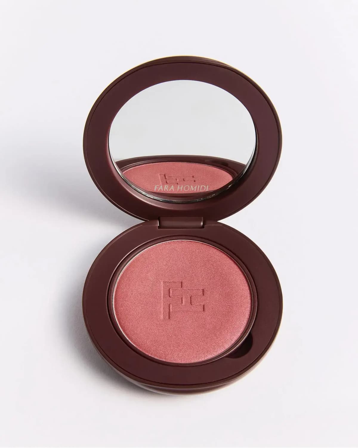 Open brown Fara Homidi compact with mirror showing a pressed rosy-pink blush embossed with the FH monogram