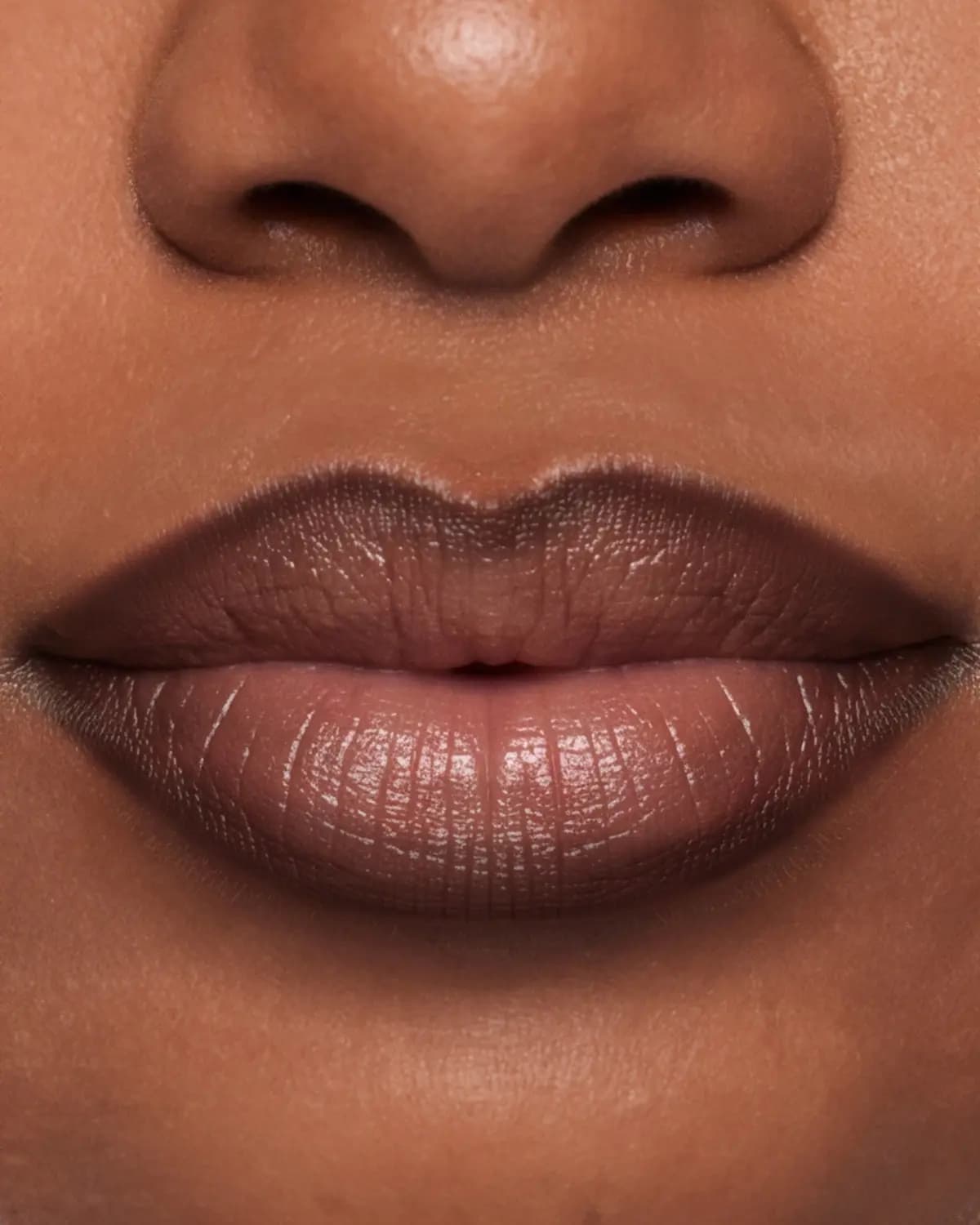 Close-up of deep-skinned lips with a dark brown lined edge blending into a lighter brown centre