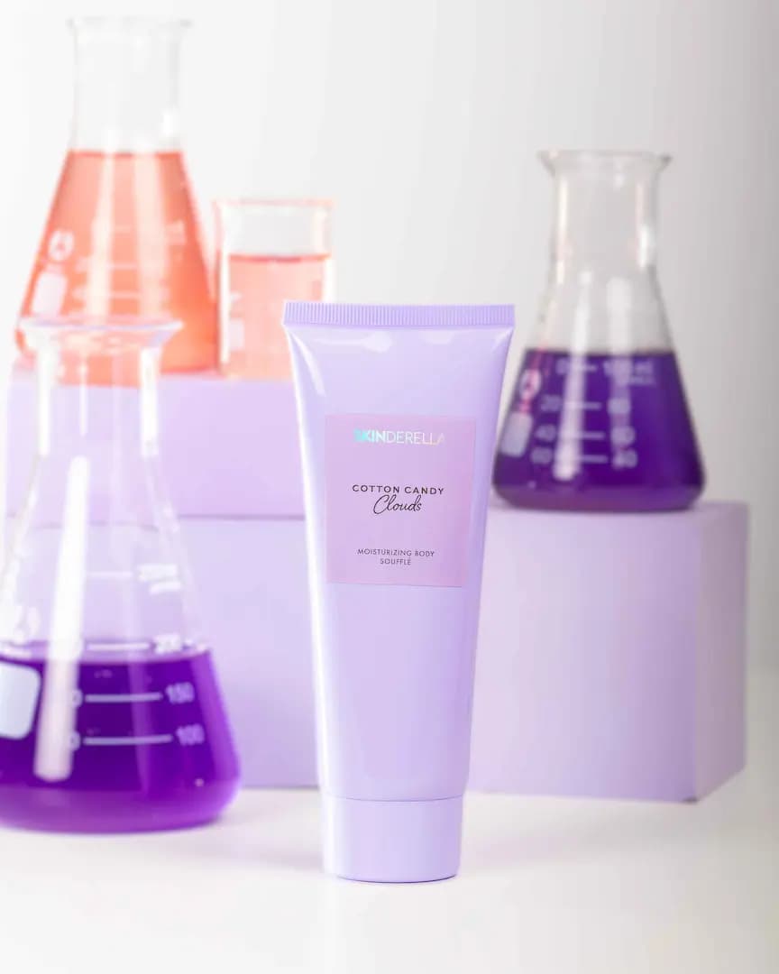 Skinderella Cotton Candy Clouds moisturising body soufflé tube beside pink and purple lab flasks