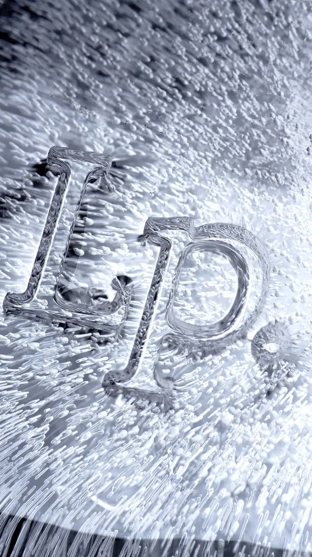 Clear ice sculpture of the Living Proof "Lp." logo embedded in frosted ice full of tiny white bubbles