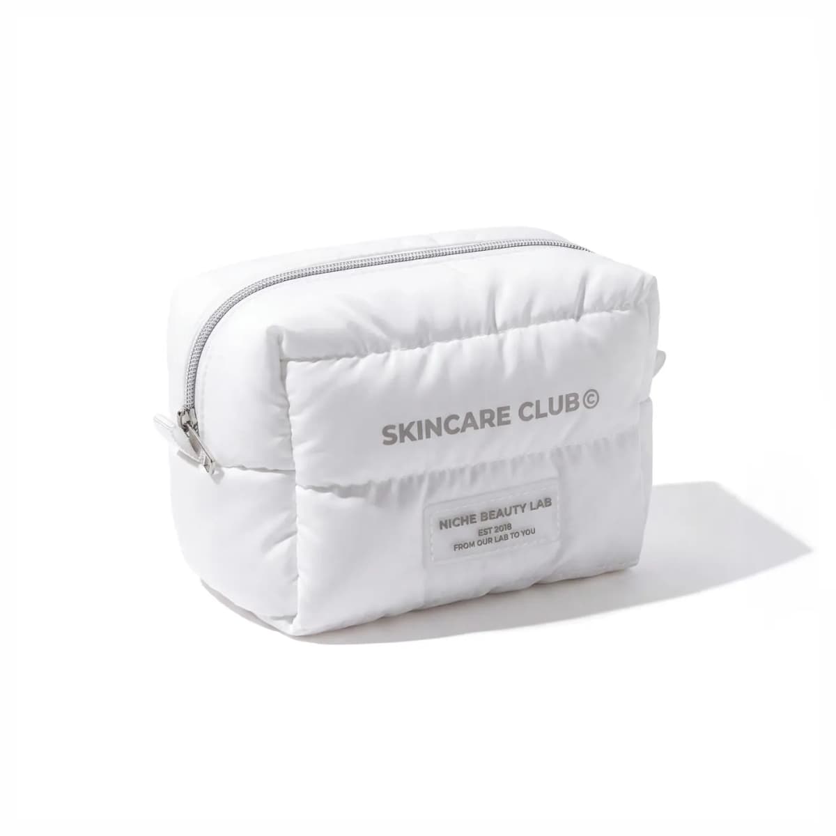 White puffy quilted zippered cosmetic pouch labelled Skincare Club with Niche Beauty Lab patch
