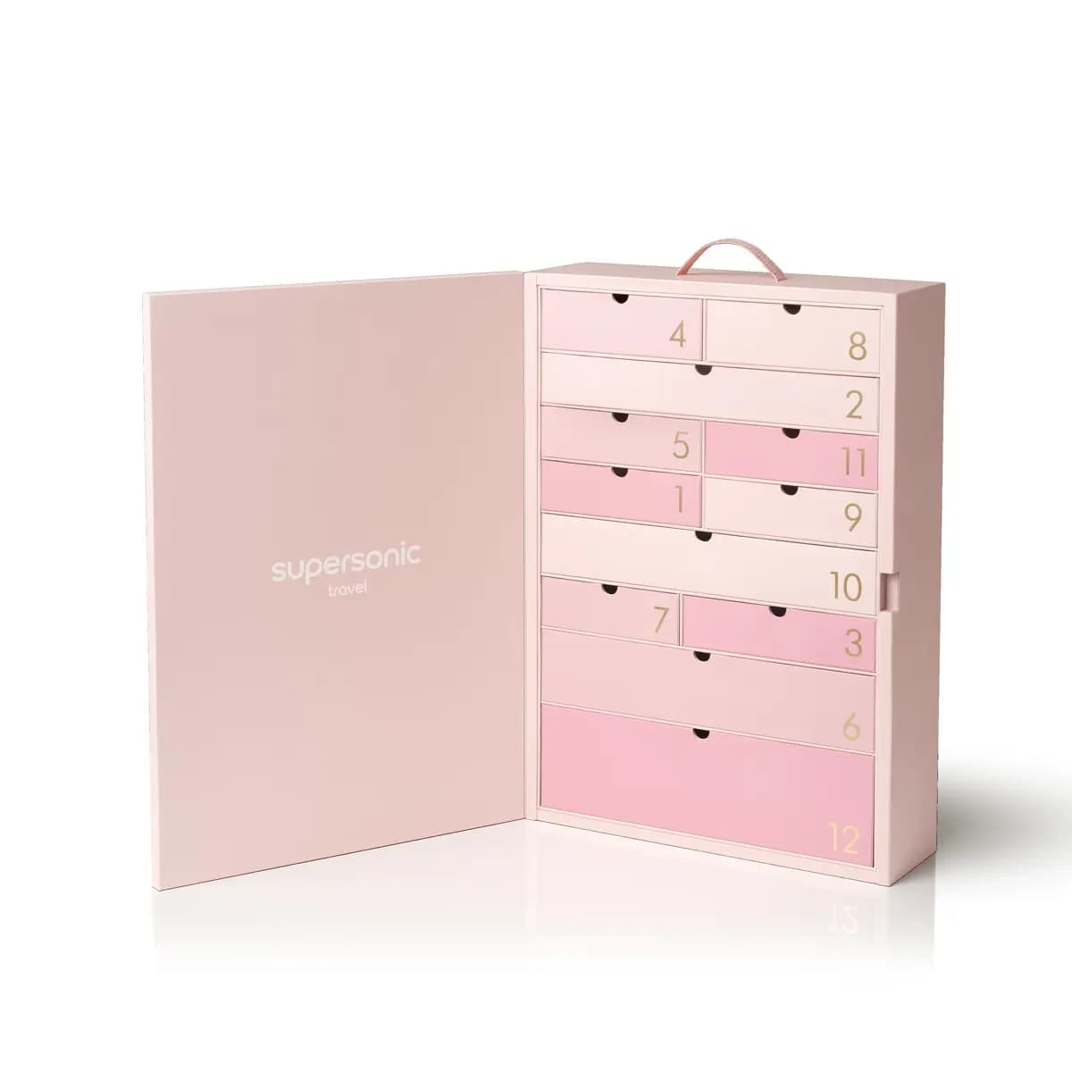 The open pink suitcase-style calendar with "supersonic travel" inside the lid and 12 numbered drawers in ombré pink