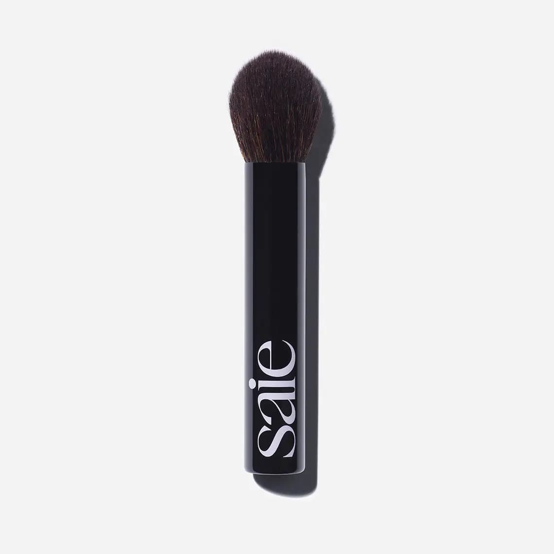 Fluffy tapered powder brush with glossy black Saie handle on a white background