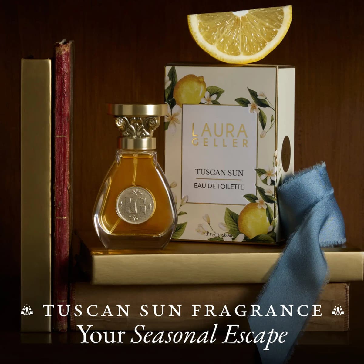 Tuscan Sun bottle and lemon-print Laura Geller box with a lemon wedge, books and blue ribbon on a dark shelf