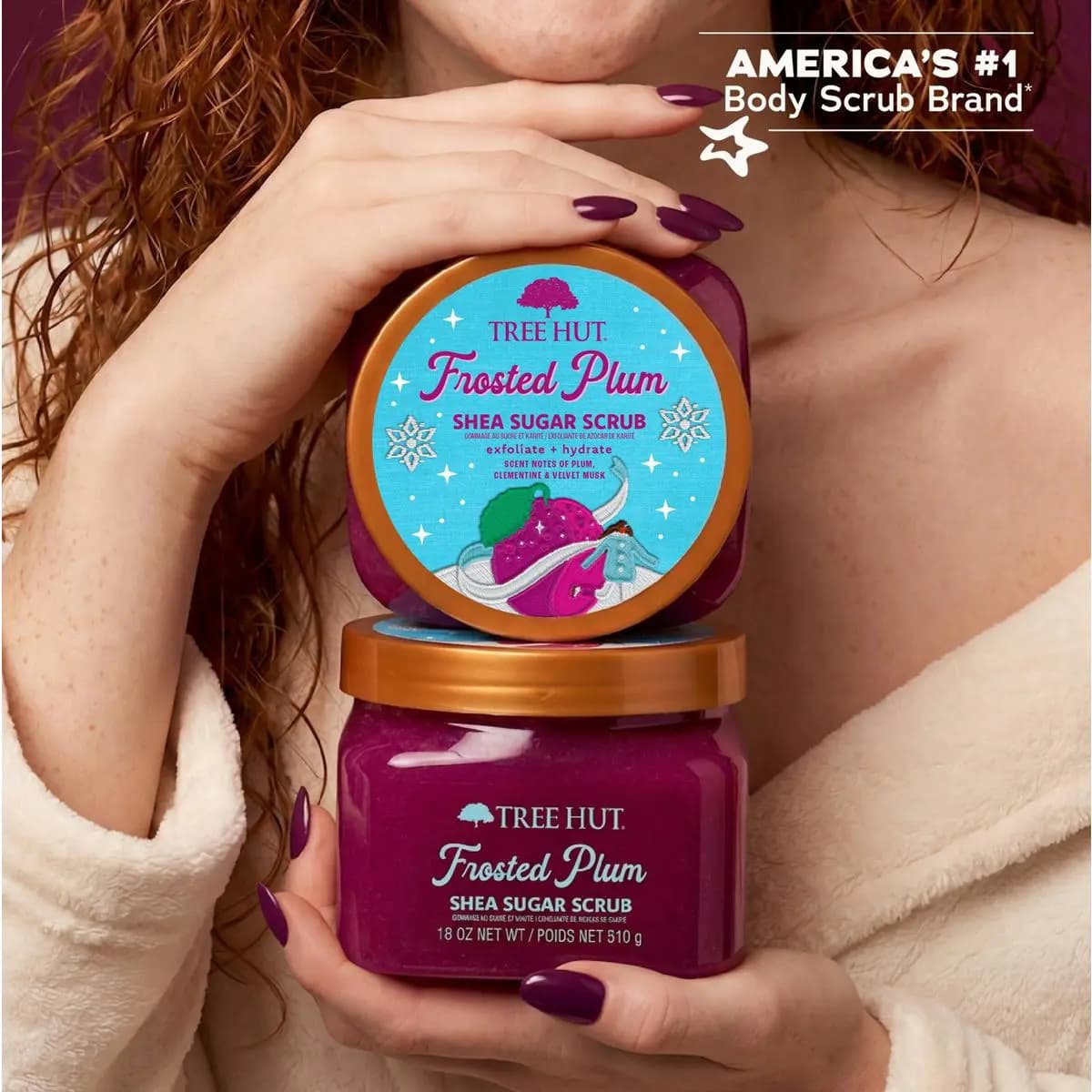 Woman with red hair holding stacked Frosted Plum Shea Sugar Scrub jars beside America's #1 Body Scrub Brand badge