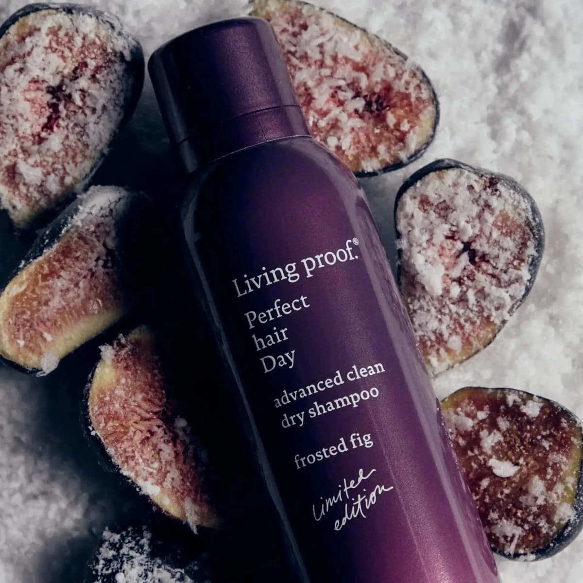 Purple Living Proof Frosted Fig dry shampoo can lying among halved figs dusted with frost on snowy white crystals