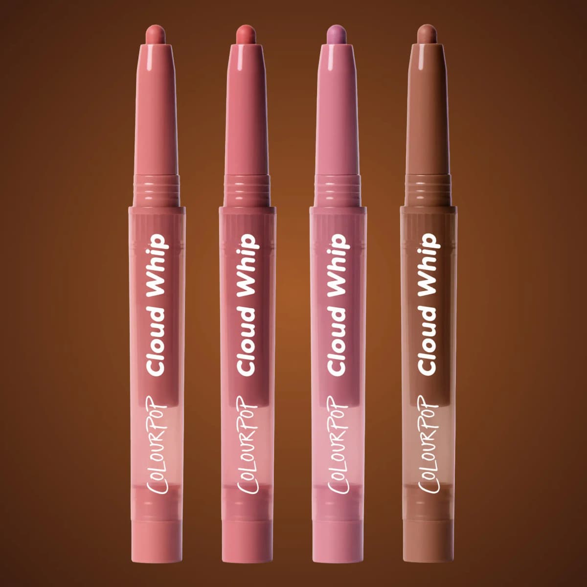 Four ColourPop Cloud Whip lip liners in pink, rose, mauve and brown on a warm brown background