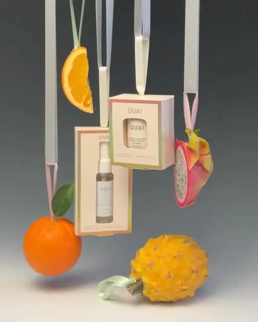 OUAI ornament boxes hanging on ribbons among suspended orange slice, orange, dragon fruit and yellow pitaya