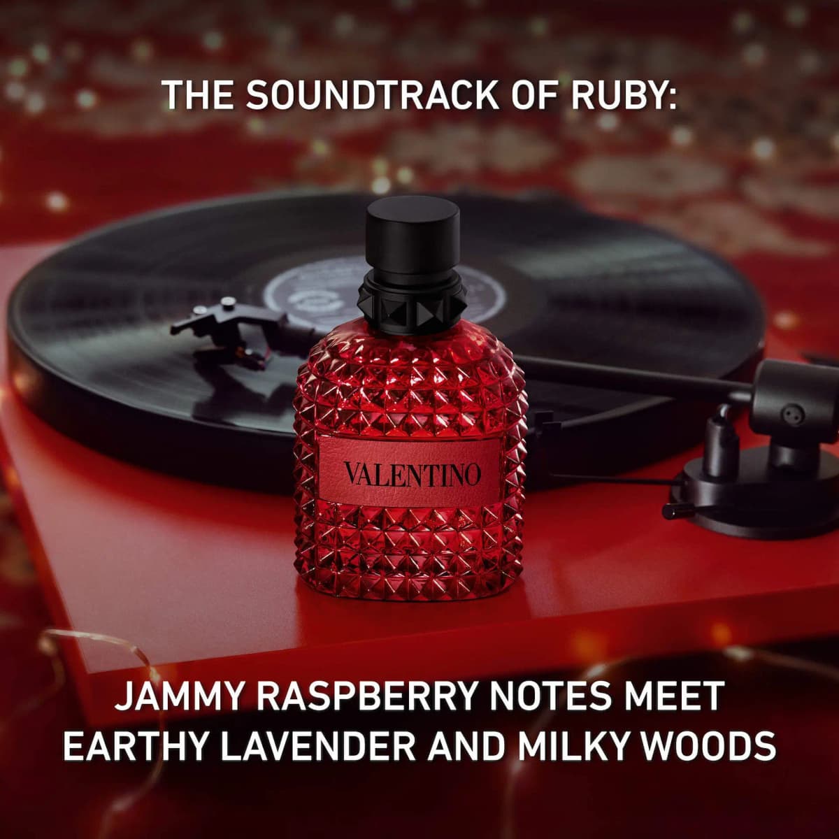 Red studded Valentino Uomo bottle on a turntable with text about jammy raspberry, lavender and milky woods.