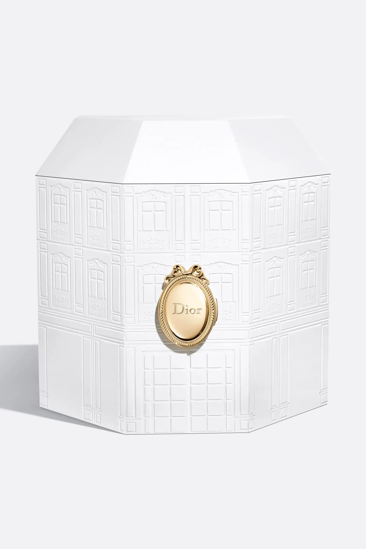 Closed white octagonal box embossed with a Parisian façade and a gold oval Dior medallion clasp