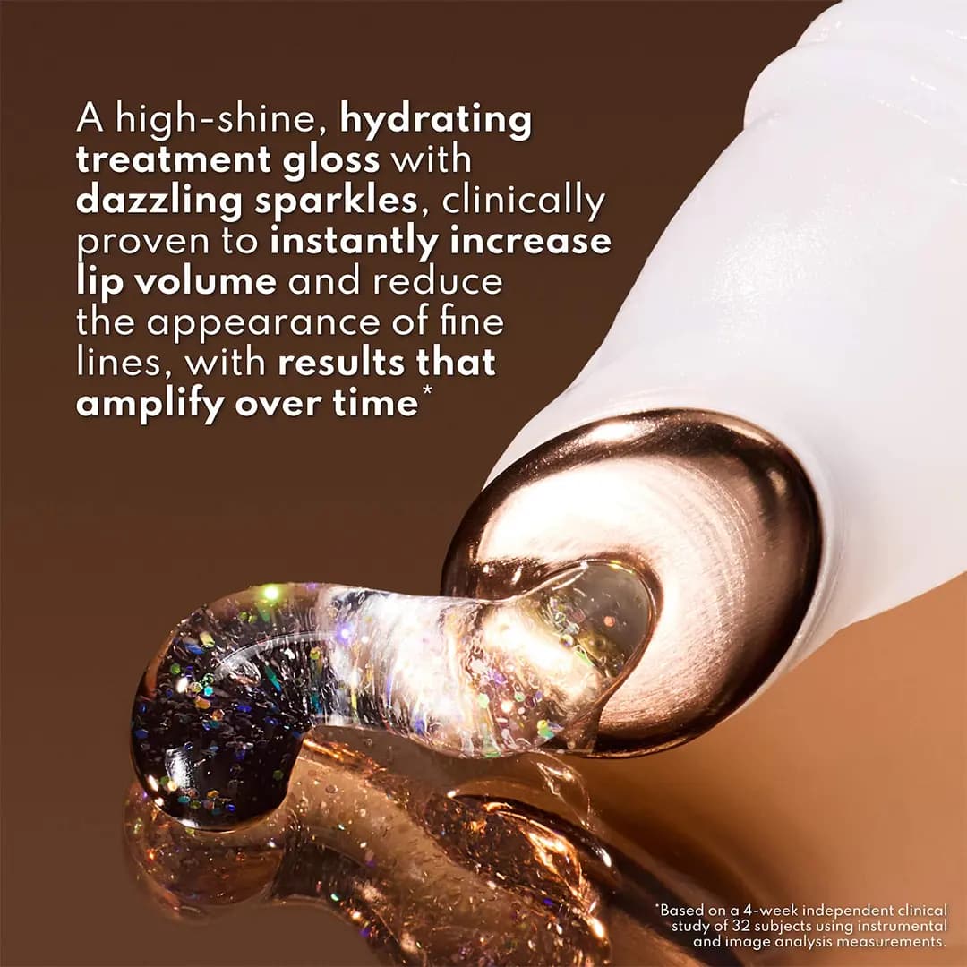 Close-up of a rose-gold metal applicator tip squeezing out clear gloss with holographic glitter flecks