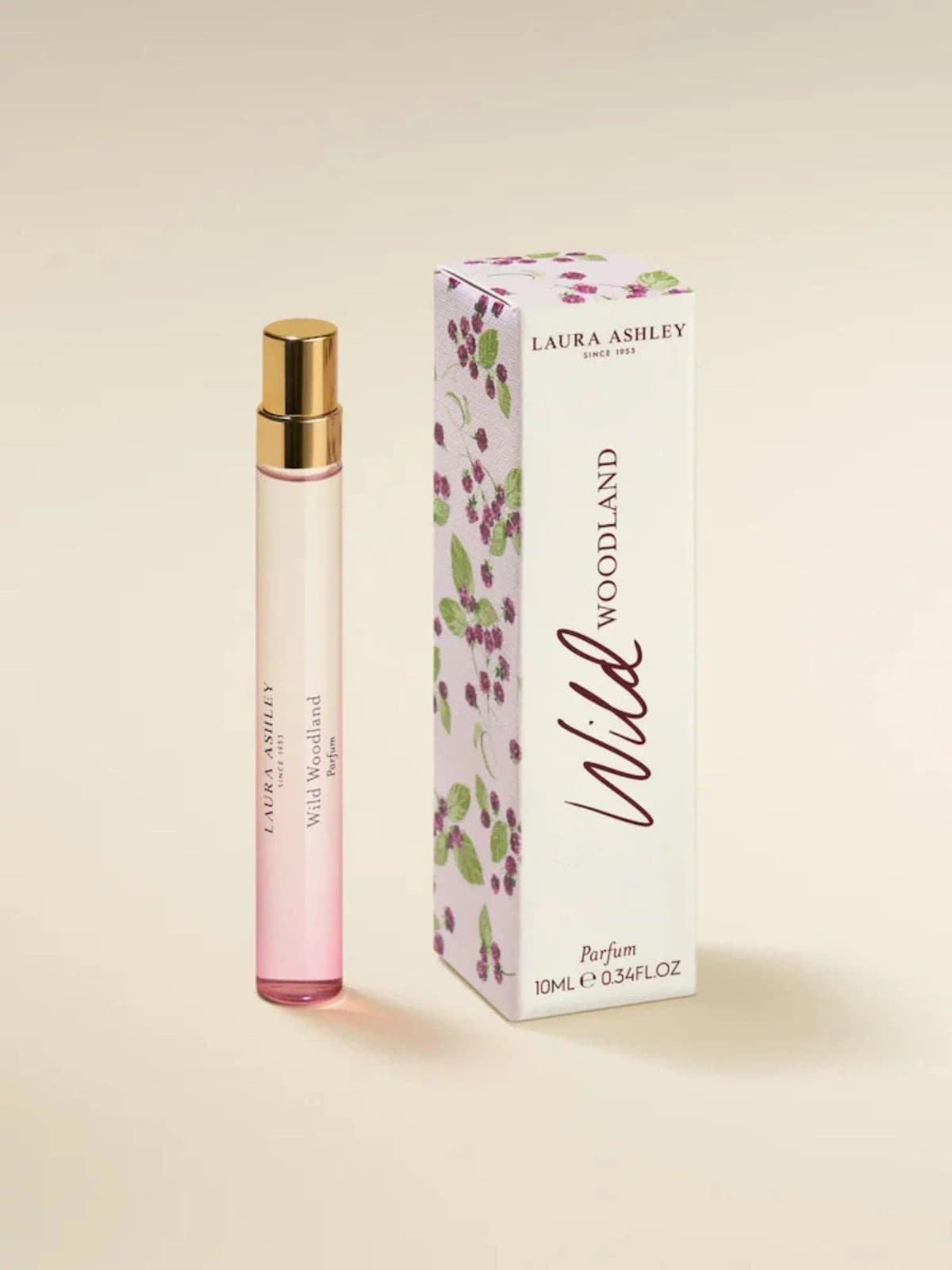 Pink-to-clear Laura Ashley Wild Woodland 10ml parfum pen spray with gold cap beside a berry-print box.