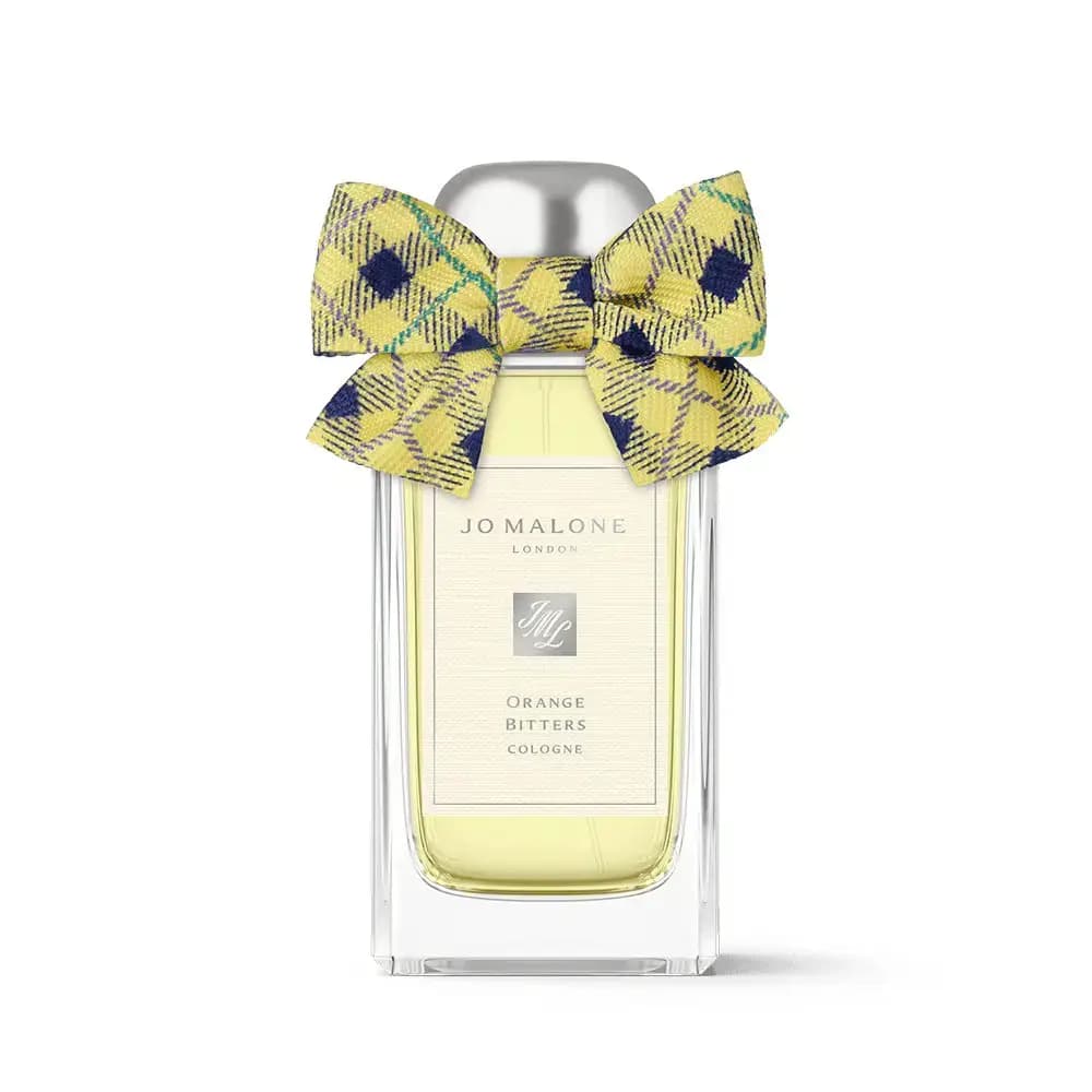 Orange Bitters Cologne bottle with a yellow tartan bow featuring navy diamonds and teal lines