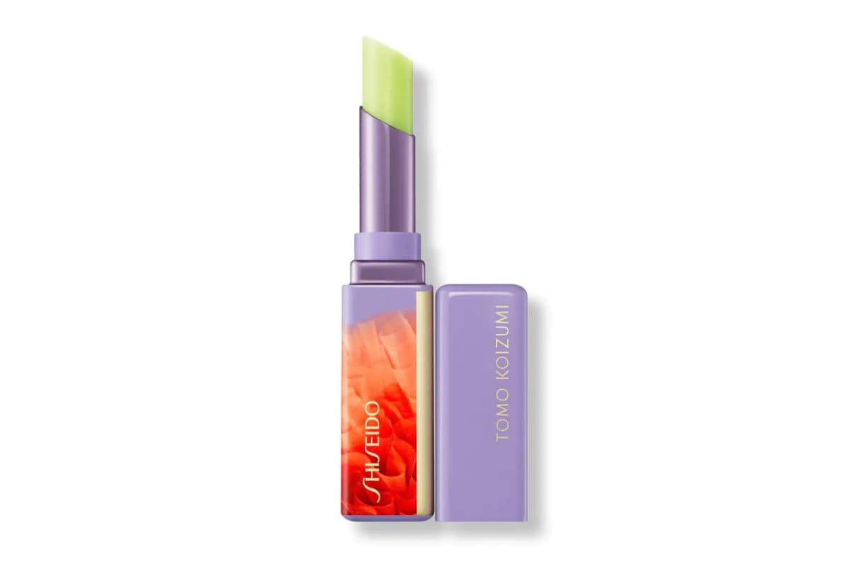 Neon green SHISEIDO lip balm in a lilac case with orange ruffle print, Tomo Koizumi cap beside it