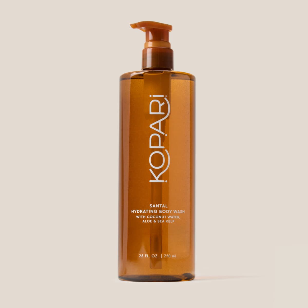 Product shot of the amber Kopari Santal Hydrating Body Wash pump bottle on a plain beige background.